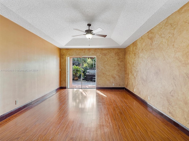 spare room featuring a textured ceiling, ceiling fan, a tray ceiling, and dark hardwood / wood-style flooring