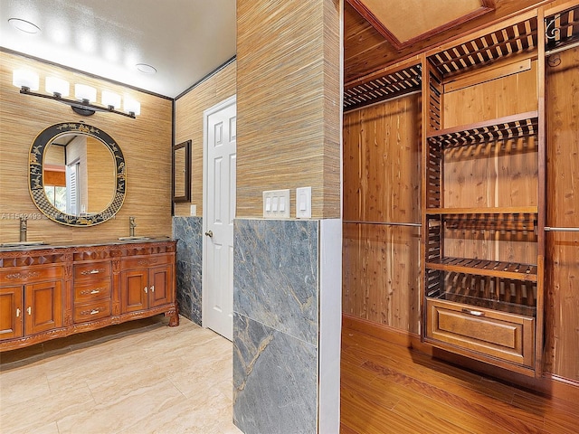 bathroom with wood walls, oversized vanity, tile floors, and double sink