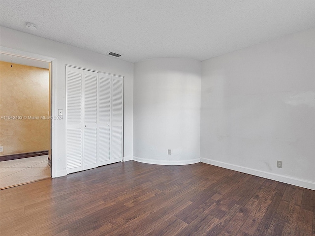 unfurnished bedroom with dark hardwood / wood-style flooring, a closet, and a textured ceiling