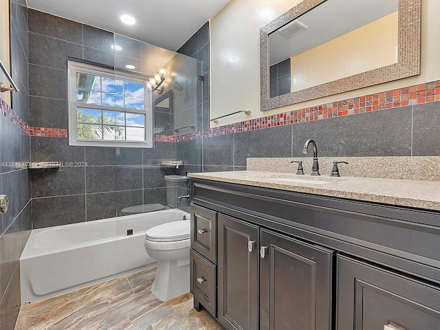 full bathroom featuring tiled shower / bath combo, tile floors, tile walls, large vanity, and toilet