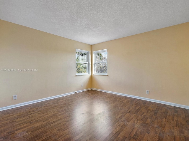 unfurnished room with a textured ceiling and dark hardwood / wood-style flooring