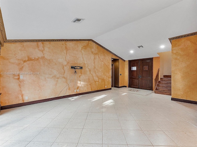 tiled empty room featuring vaulted ceiling