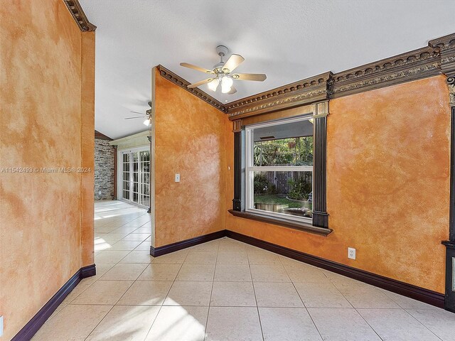 tiled spare room featuring lofted ceiling, ceiling fan, and a textured ceiling