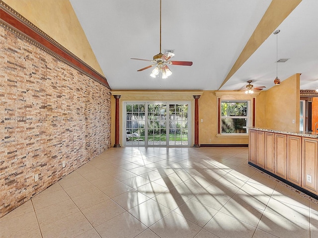 unfurnished living room featuring brick wall, vaulted ceiling, ceiling fan, and light tile floors