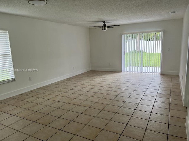 unfurnished room featuring a textured ceiling, ceiling fan, and light tile floors