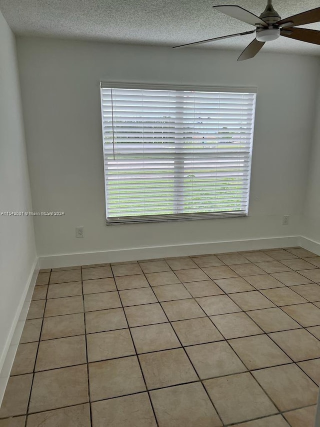 empty room featuring ceiling fan, a textured ceiling, and light tile flooring