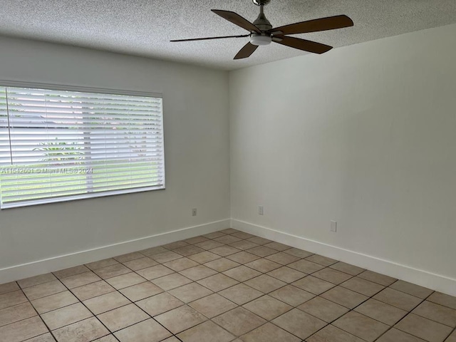 empty room featuring a textured ceiling, ceiling fan, and light tile floors