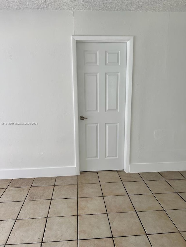 tiled empty room featuring a textured ceiling