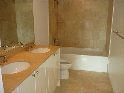 full bathroom with dual bowl vanity, bathing tub / shower combination, toilet, and tile floors