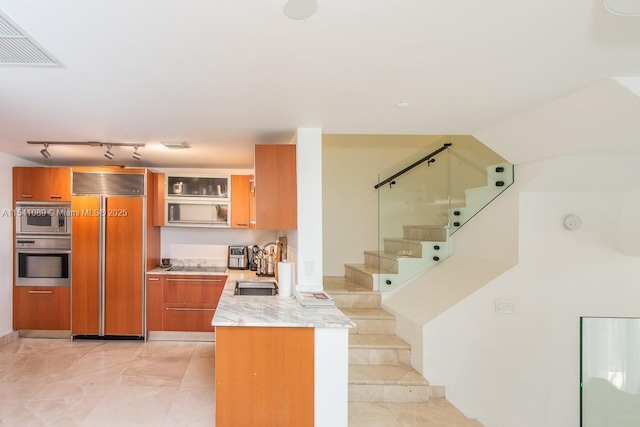 kitchen featuring light tile patterned flooring, built in appliances, rail lighting, and sink