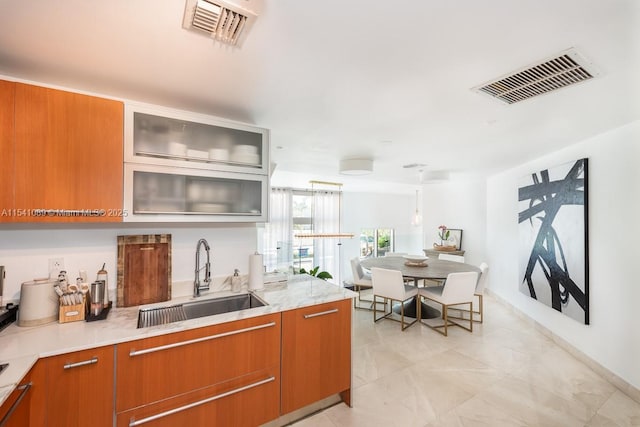 kitchen with brown cabinetry, visible vents, and a sink