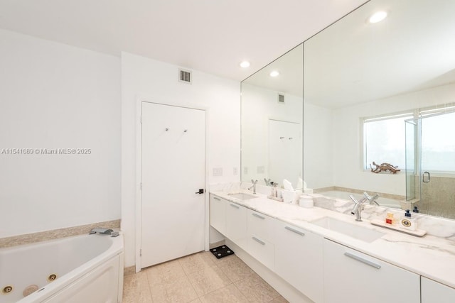 full bathroom featuring double vanity, a tub with jets, visible vents, and a sink