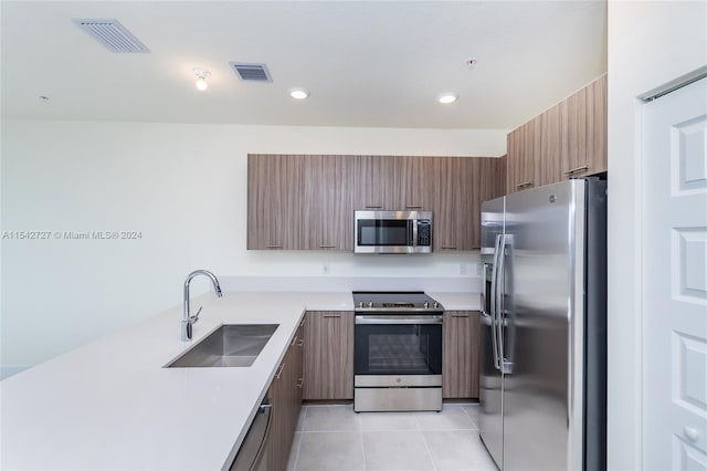 kitchen featuring stainless steel appliances, sink, and light tile floors