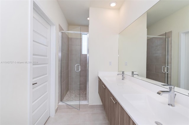 bathroom with tile floors, vanity with extensive cabinet space, double sink, and walk in shower