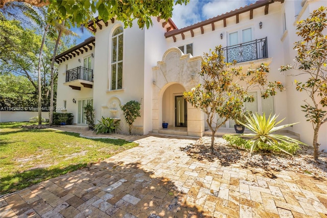 view of front of property featuring a balcony and a front lawn