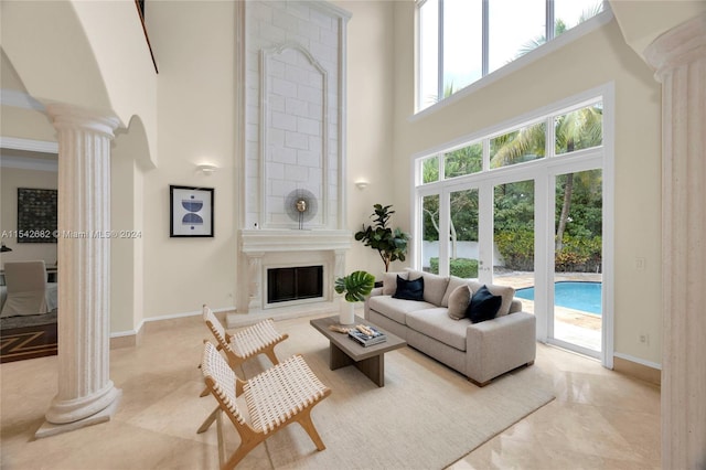 living room with a fireplace, decorative columns, and a high ceiling