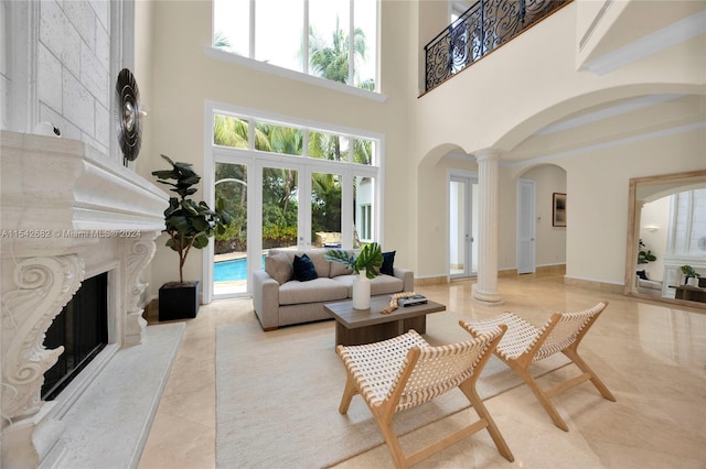 living room featuring a fireplace, french doors, plenty of natural light, and ornate columns