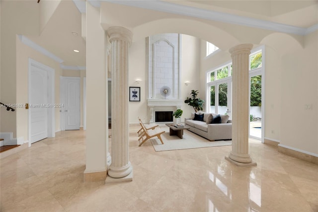 living room featuring decorative columns, crown molding, and a towering ceiling