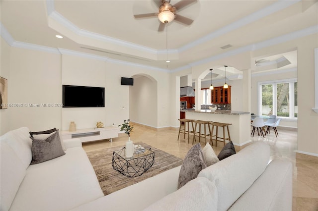 living room featuring ornamental molding, a raised ceiling, and ceiling fan