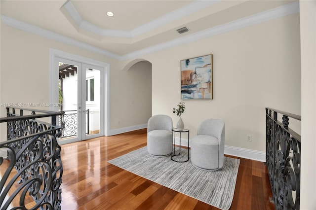 sitting room with hardwood / wood-style flooring, ornamental molding, a raised ceiling, and french doors