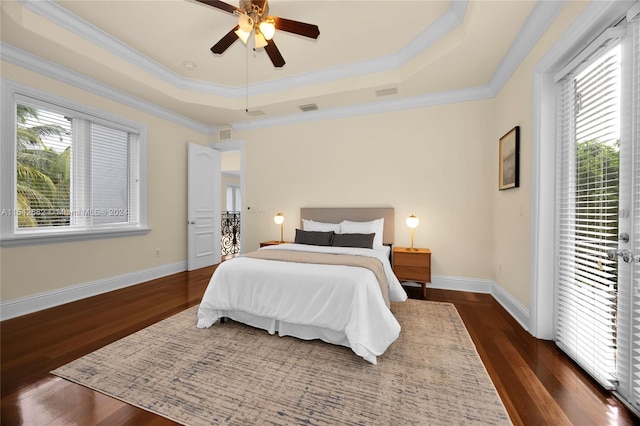 bedroom featuring dark wood-type flooring, access to outside, and a tray ceiling