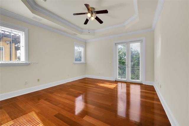 unfurnished room with hardwood / wood-style floors, a tray ceiling, ornamental molding, and ceiling fan