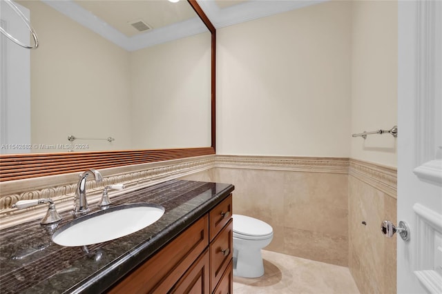 bathroom with tile patterned flooring, vanity, tile walls, and toilet