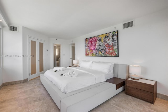 bedroom with ensuite bathroom, french doors, and light tile flooring