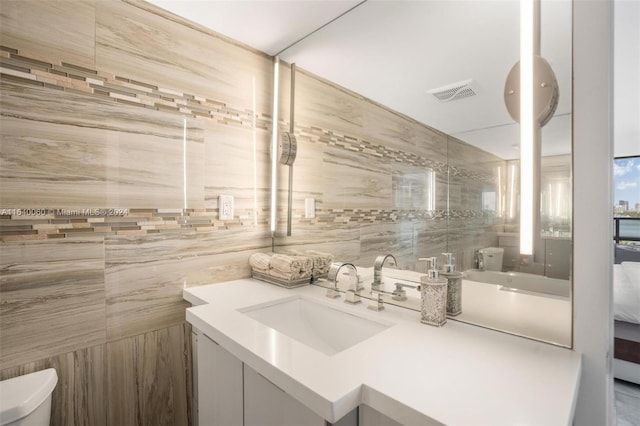 bathroom featuring oversized vanity, toilet, and tile walls