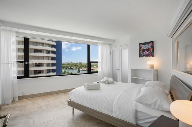 bedroom with a water view and light tile floors