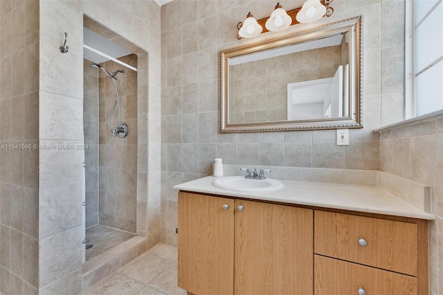 bathroom with tile floors, tiled shower, vanity with extensive cabinet space, and tile walls