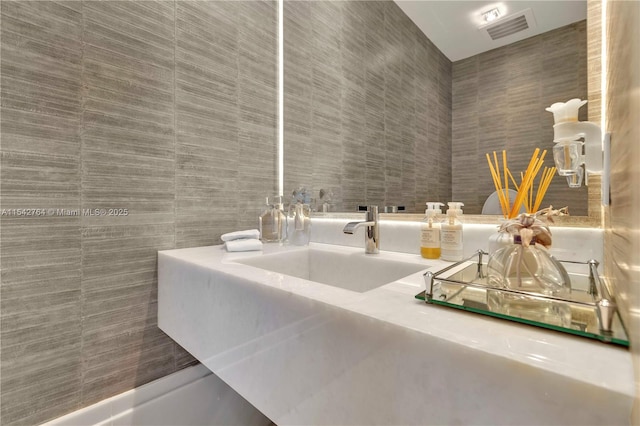 bathroom featuring tile walls, visible vents, and a sink