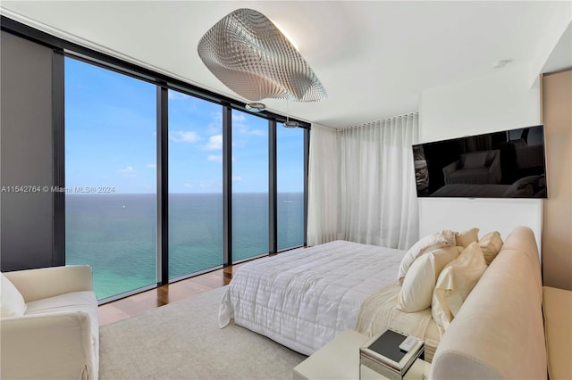 bedroom featuring floor to ceiling windows, a water view, and light wood-type flooring