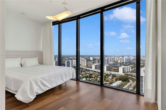 bedroom with a wall of windows and dark hardwood / wood-style flooring