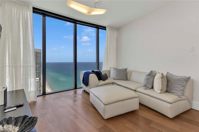 living room featuring a water view, light hardwood / wood-style flooring, and a wall of windows