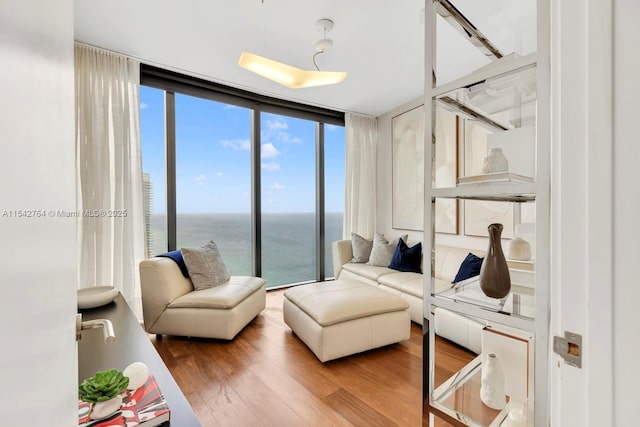 living area with wood finished floors, a water view, and expansive windows