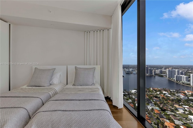 bedroom featuring hardwood / wood-style floors, floor to ceiling windows, and a water view