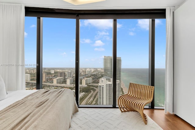 bedroom with a city view, a wall of windows, and wood finished floors