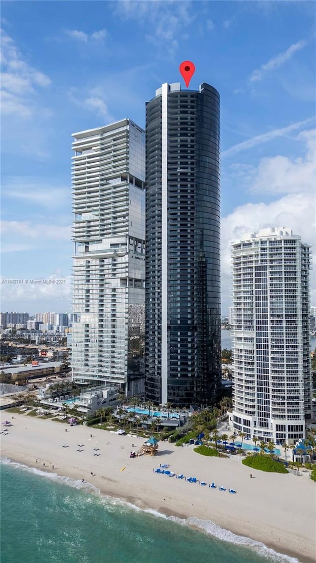 view of building exterior featuring a view of the beach, a view of city, and a water view