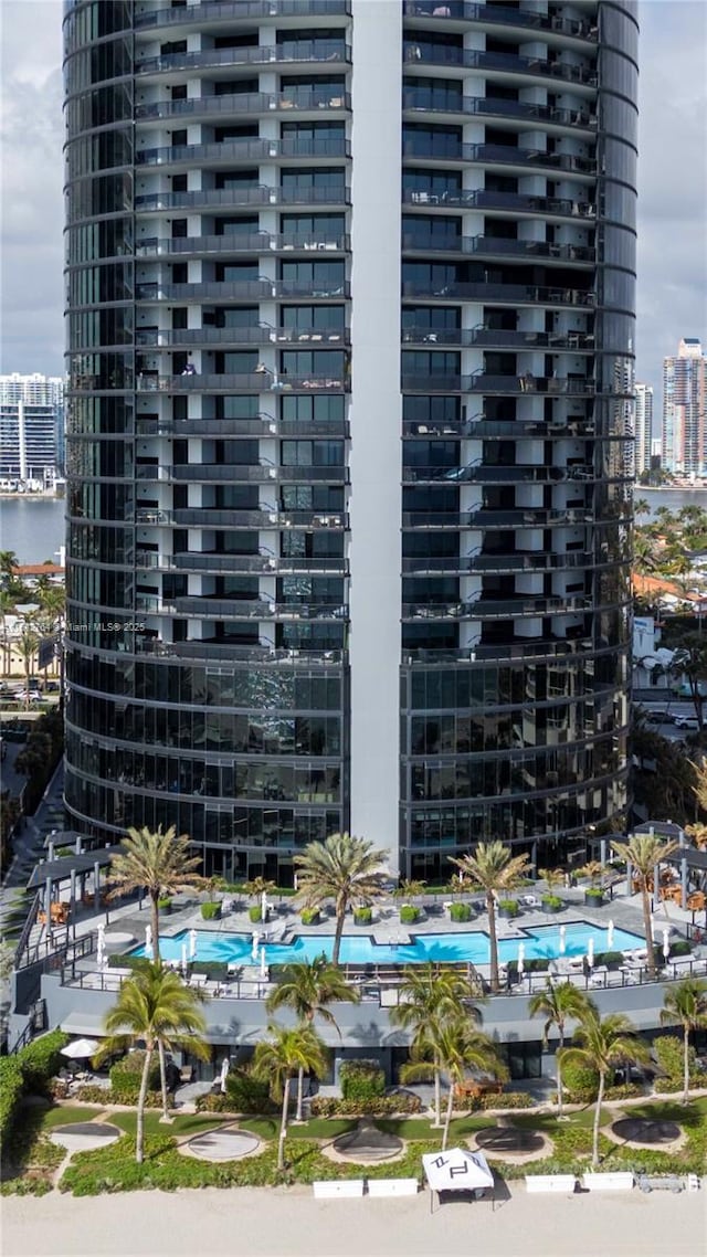 view of building exterior with a view of city, a community pool, and a water view