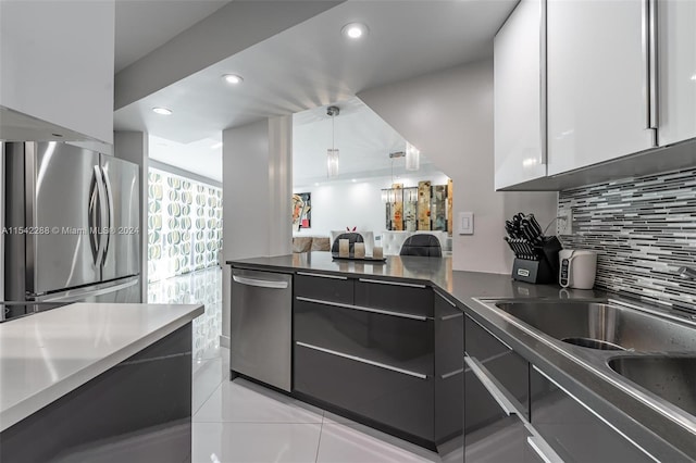 kitchen with appliances with stainless steel finishes, sink, white cabinetry, hanging light fixtures, and light tile patterned flooring