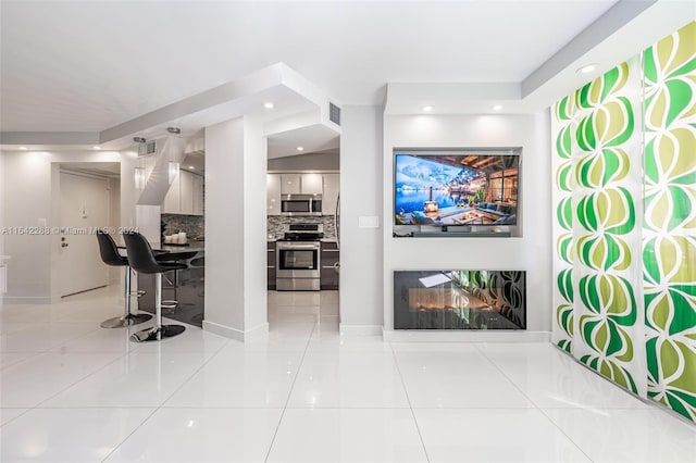 interior space with backsplash, tile patterned floors, and appliances with stainless steel finishes