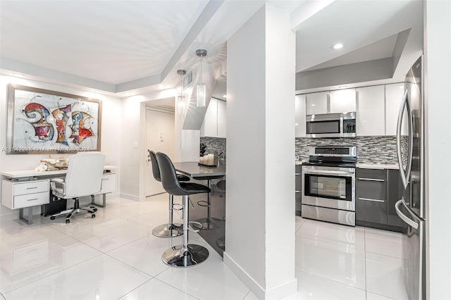 kitchen featuring appliances with stainless steel finishes, tasteful backsplash, light tile patterned floors, white cabinetry, and hanging light fixtures