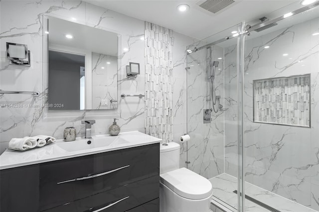 bathroom featuring vanity, toilet, a shower with shower door, and tile walls