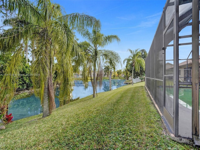 view of yard with a lanai and a water view