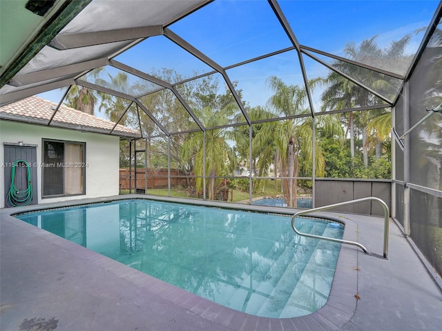 view of swimming pool featuring glass enclosure and a patio area