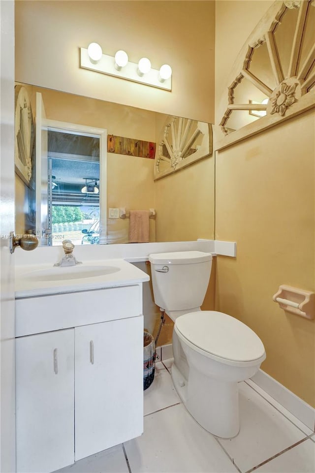 bathroom with toilet, vanity, and tile flooring