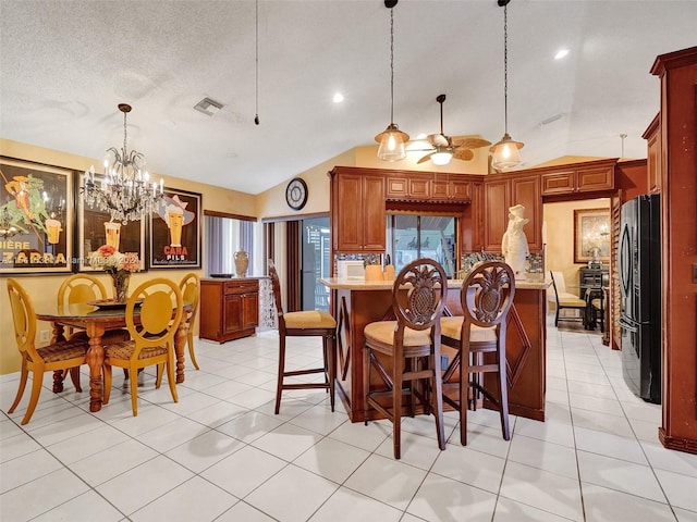 kitchen with a kitchen breakfast bar, decorative light fixtures, vaulted ceiling, and refrigerator