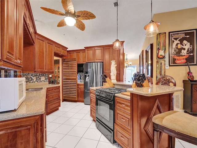 kitchen with light tile floors, hanging light fixtures, black gas stove, backsplash, and ceiling fan with notable chandelier