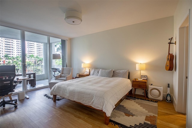 bedroom with expansive windows, light hardwood / wood-style floors, and access to outside